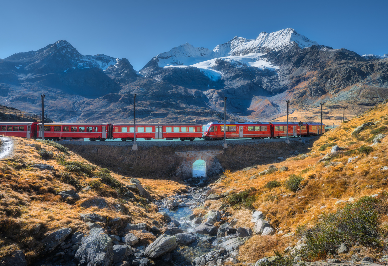 Le train Bernina Express traversant un paysage alpin avec un glacier, Suisse. © iStock / den-belitsky